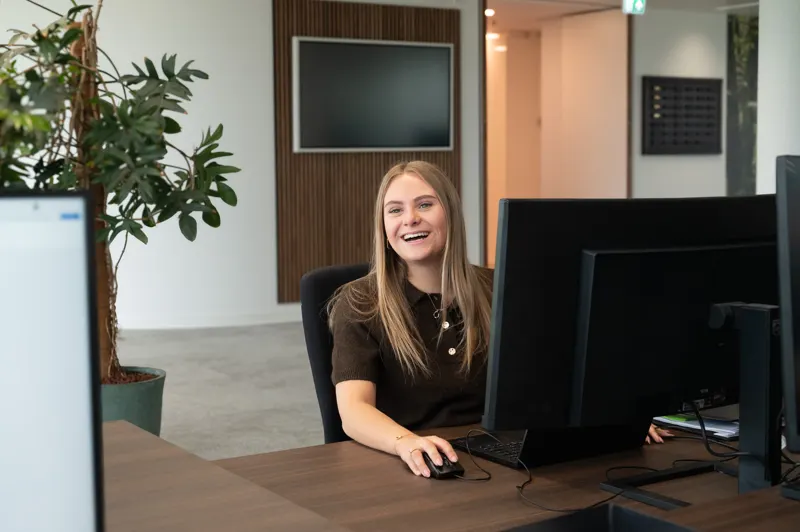 Collega lacht achter haar bureau op kantoor