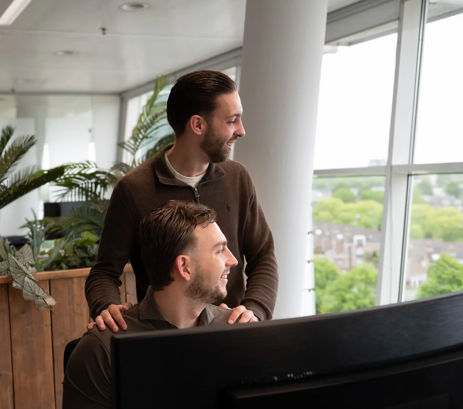 Twee collega's kijken samen naar een scherm
