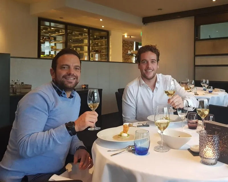 Twee collega's proosten aan tafel bij de start van BURG